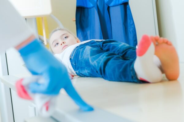 Małe dziecko w gabinecie pediatrycznym leży na stole podczas badania.